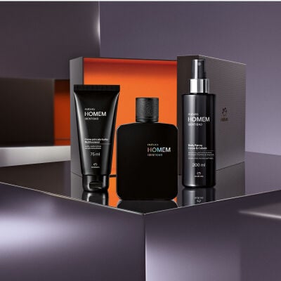 Kit Natura Homem Identidad posicionado sobre uma superfície espelhada à frente de uma caixa aberta. Inclui um creme pré e pós-barba, a colônia em frasco preto fosco e um body spray.