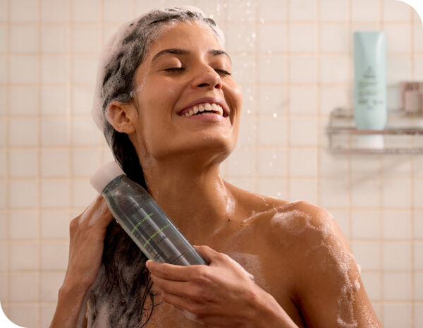 Mulher sorridente no banho com espuma no cabelo usando o Shampoo hidratante Tododia Maçã Verde e Aloe Vera