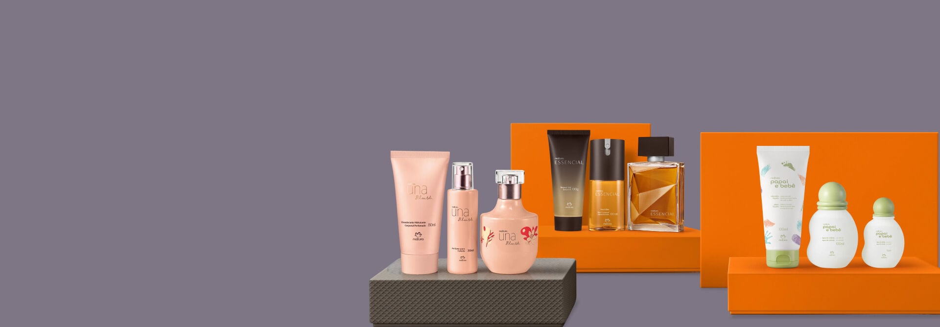 presente Natura Una Blush apoiado sobre caixa cinza, presente essencial masculino e presente natura mamãe e bebê apoiados sobre caixas laranjas, em fundo cinza