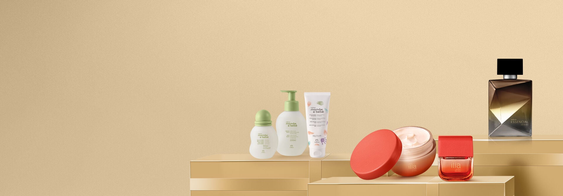 Diversos produtos Natura organizados sobre caixas douradas em fundo bege. À esquerda, itens Mamãe e Bebê; ao centro, creme e perfume Ilía Jardim Secreto; à direita, perfume Essencial Desejos.