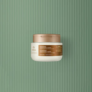 Frasco creme com tampa e rótulo dourados de Leave-in Densificador Antissinais Natura Lumina. Fundo em verde com listras verticais.