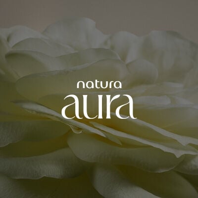 Texto em branco Natura Aura, em fundo creme com flor de pétalas brancas. 