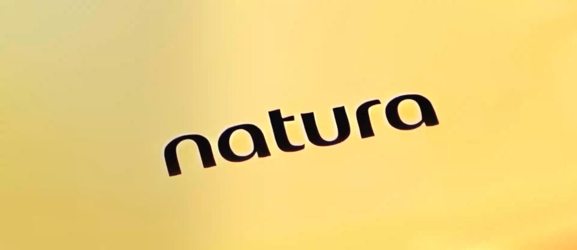 Desodorante Colônia Humor é borrifado em fundo branco. Suas gotas, ampliadas, contêm ingredientes como pêssego, laranja, framboesa e lavanda. Um cérebro colorido e brilhante ilustra como a fragrância age nas emoções. Frascos das fragrâncias + Ânimo, + Confiança e + Vibrações se destacam em meio a neurônios coloridos. Uma mulher branca jovem borrifa a fragrância no pescoço, cercada por amigos. 