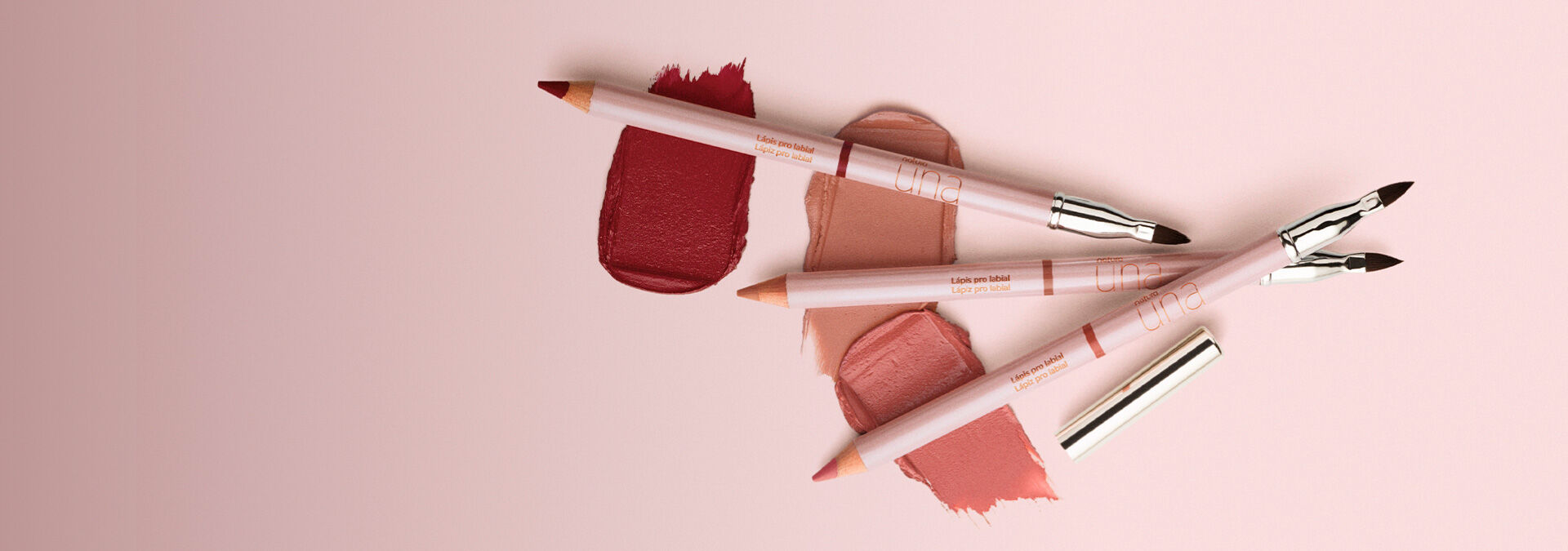 Imagen con fondo rosa claro y a la derecha tres lápices labiales con colores y texturas diferentes.