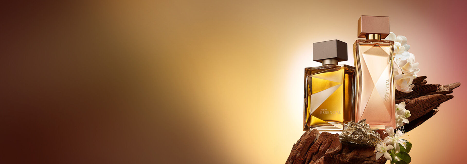Dos frascos de perfume Essencial sobre madera decorada con flores blancas, con un fondo degradado en tonos dorados y marrones