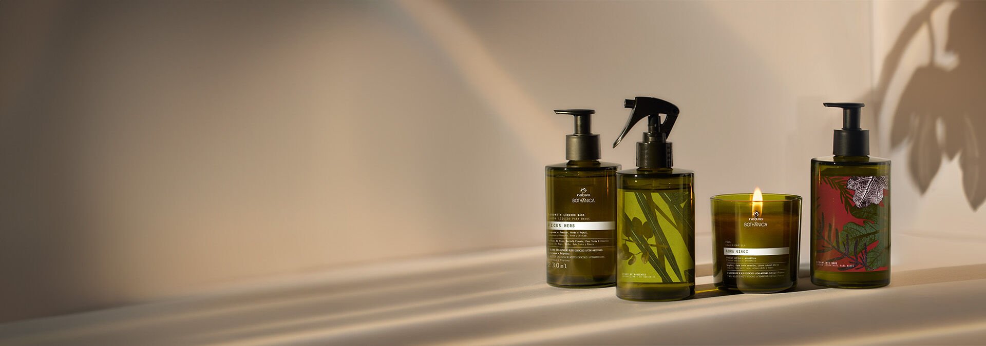 Cuatro frascos de productos Natura Bothanica en tonos verdes y marrones, alineadas sobre una superficie clara.
