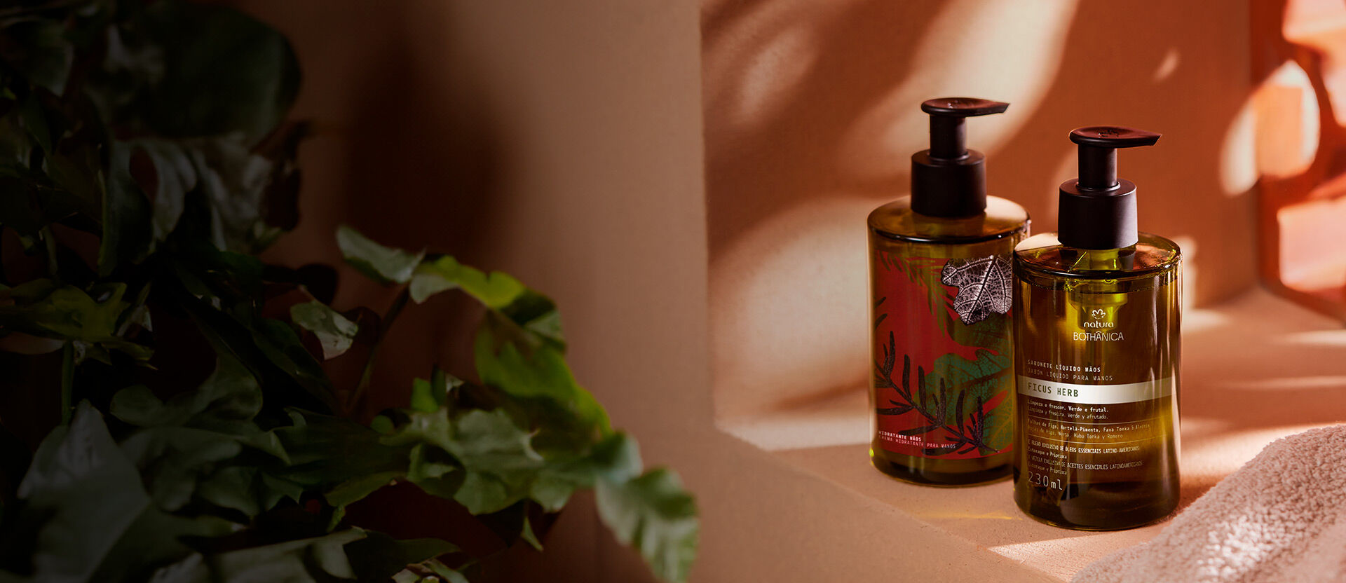 Frascos de productos Natura Bothanica en tonos verdes y marrones sobre una superficie beige, con follaje al fondo.