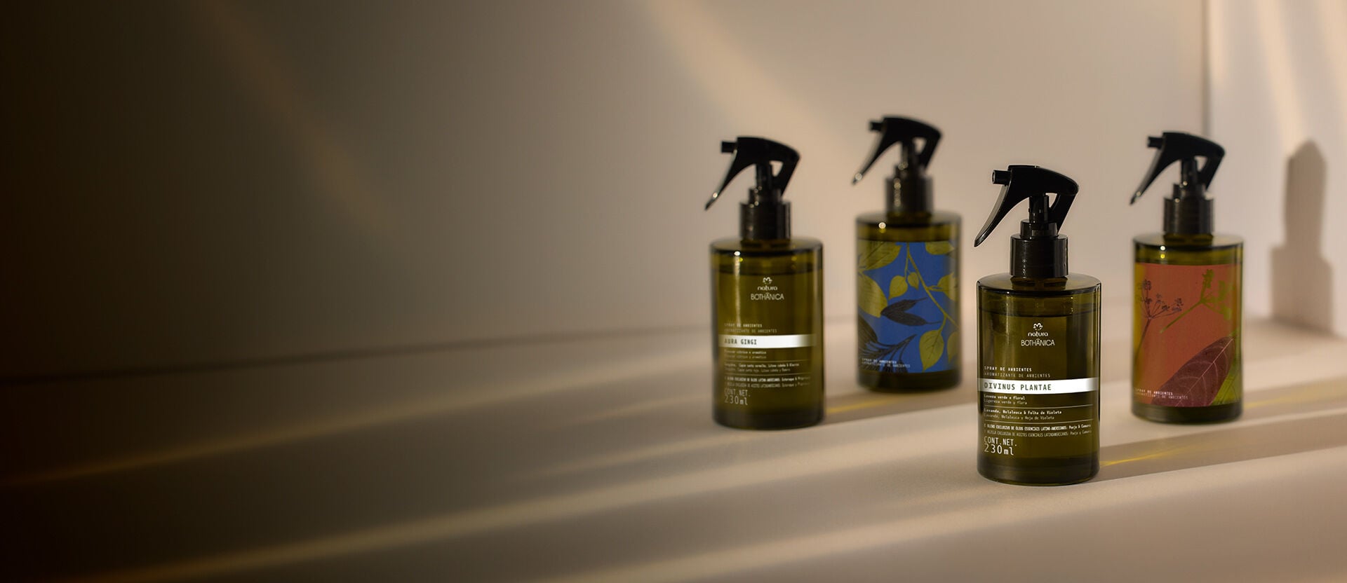 Cuatro frascos de productos Natura Bothanica en tonos verdes y marrones, alineadas sobre una superficie clara.