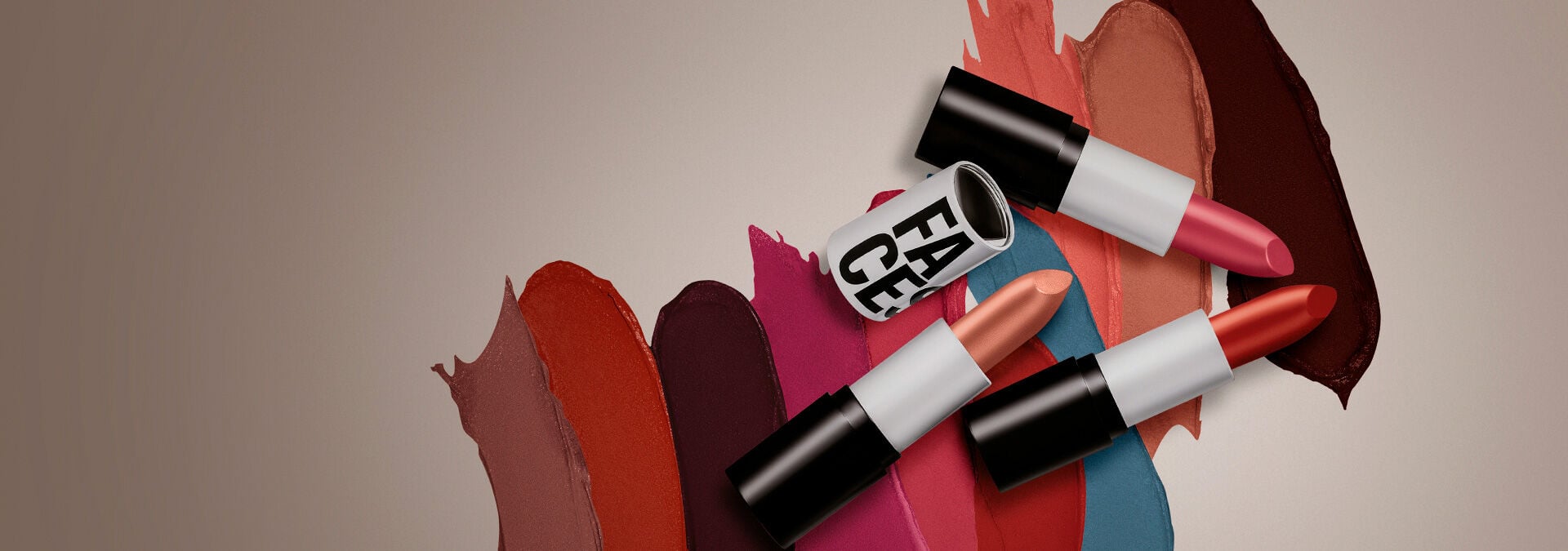 Fondo claro con tres labiales Faces abiertos en la parte derecha, mostrando la textura y el color de los labiales en el fondo.