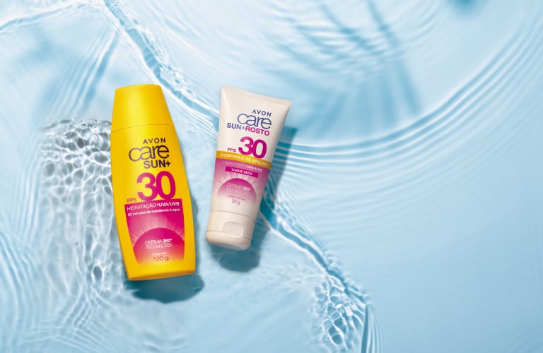 Dois frascos de protetor solar Avon Care Sun FPS 30 dispostos sobre uma superfície com água azul translúcida em movimento e sombras de folhas de palmeira ao fundo. À esquerda, um frasco grande amarelo e, à direita, um frasco menor em formato de bisnaga branca com detalhes em rosa e amarelo.