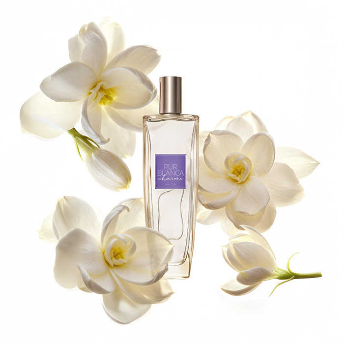 Frasco da fragrância Pur Blanca Charme, rodeada de flores brancas, em fundo branco.