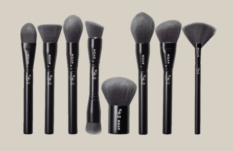 Oito tipos de pincéis de maquiagem com as cerdas cinzas e o cabo preto. Eles estão dispostos um ao lado do outro na vertical.