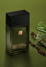 Fragrância Black Essential Real com ingredientes como pimentas e plantas, em fundo verde.