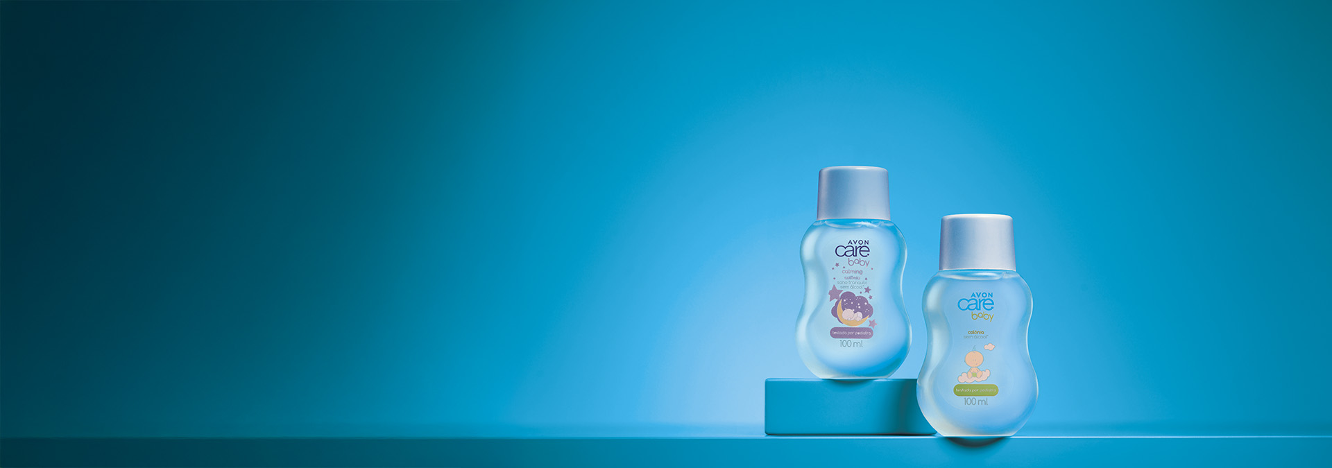 Banner com fundo azul em tons degradê. Dois frascos de produtos infantis Avon Care Baby estão centralizados, um com tema noturno e outro diurno. Texto: "Cuidado que você confia para seu pequeno."