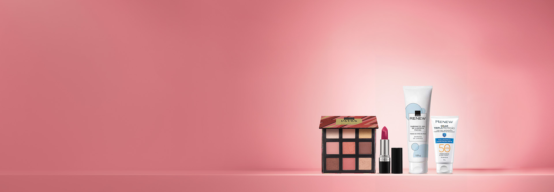 Produtos Avon sobre bancada em rosa-claro e fundo na mesma cor.