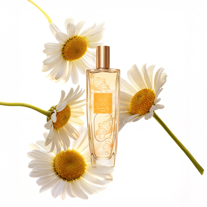 Frasco da fragrância Pur Blanca Serenity, rodeada de margaridas, em fundo branco.