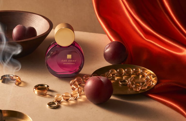 Perfume assinatura da Far Away Splendoria de Avon, ao lado de ingredientes especiados e incensos acesos.