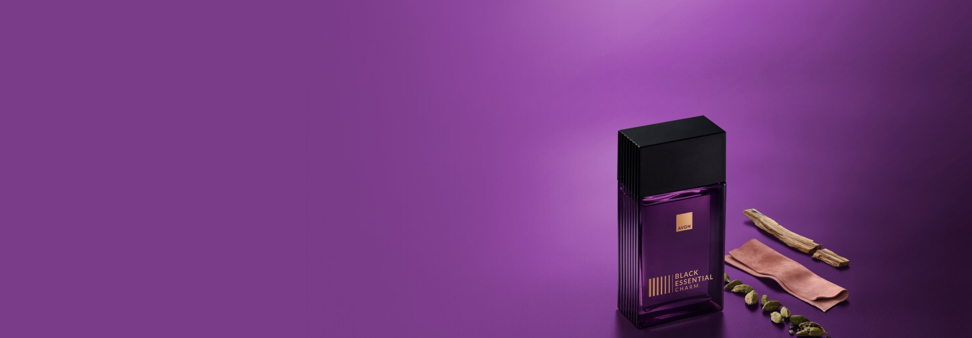 Black Essential Charm, com frasco de vidro retangular violeta, letras douradas e tampa preta, aparece ao lado de amostras de cardamomo, couro e sândalo, ingredientes da fragrância. Fundo violeta.