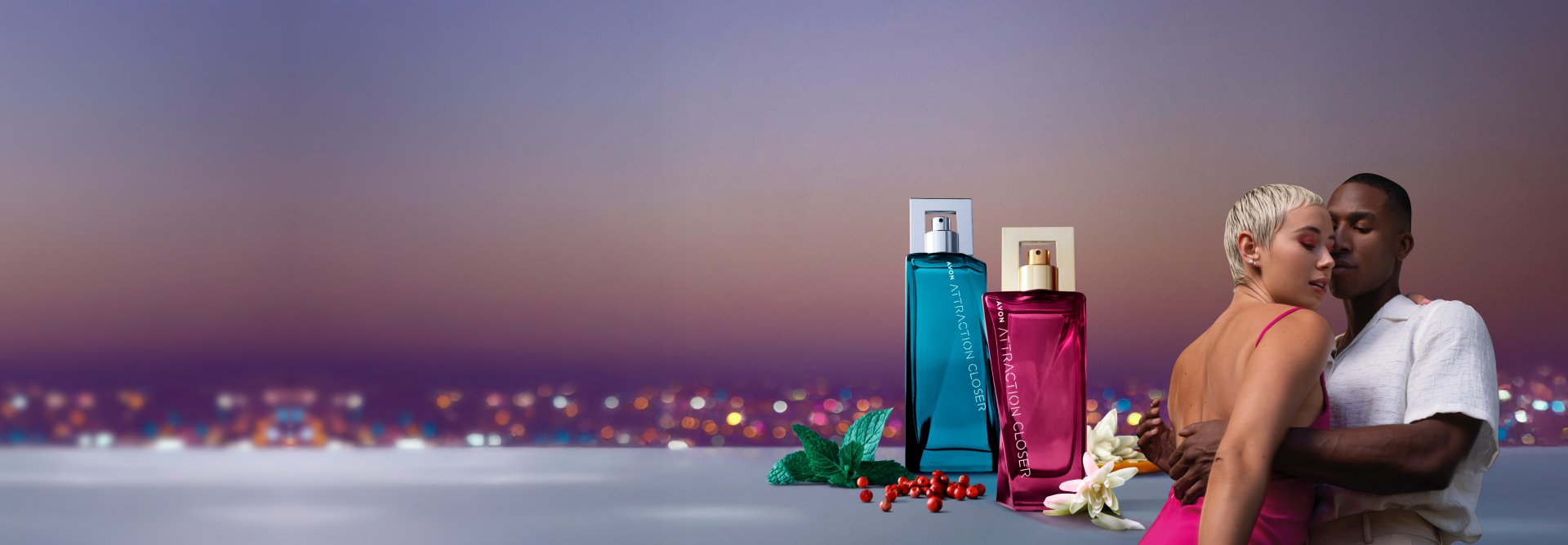 À direita, casal abraçado. Ao lado, fragrâncias Avon Attraction Closer Para Ele e Para Ela em bancada com ingredientes em fundo de horizonte iluminado.
