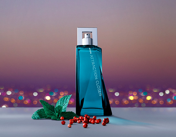 Fragrância Avon Attraction Closer para Ele em bancada cinza com ingredientes, como menta e pimenta, em fundo de entardecer de uma cidade iluminada.