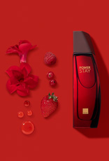 Frasco de fragrância Power Stay em vermelho sobre fundo vermelho com ingredientes como flores, framboesa,  mirtilo e morango, à esquerda.