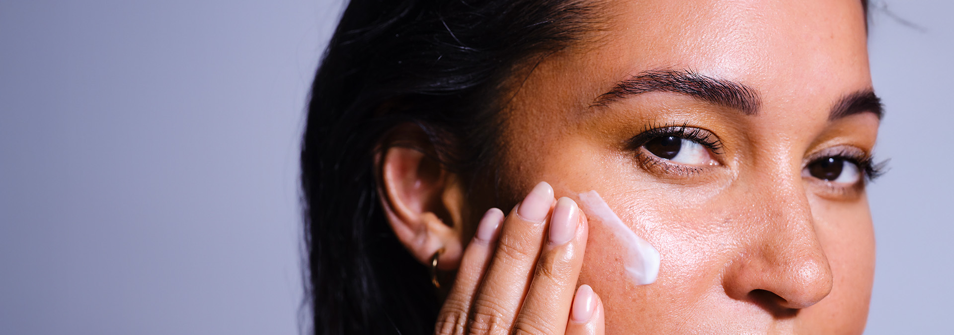 Banner com fundo suave em tons de lilás. Elementos incluem uma modelo que destaca cuidados faciais. Texto: "Descubra como cuidar da sua pele e realçar seu brilho!"