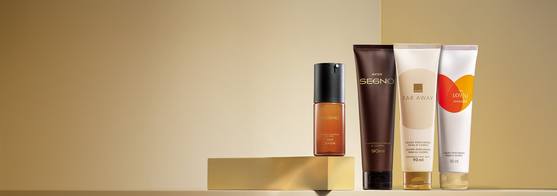 Banner com fundo dourado. Elementos incluem perfume Segno, shampoo Segno e loção Far Away sobre uma base dourada. Texto: "Corpo e Banho: presentes Avon para todos, da lembrancinha ao presentão."