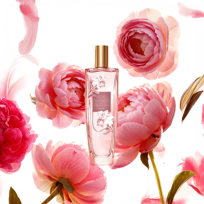 Frasco da fragrância Pur Blanca My Essence, rodeada de flores rosadas, em fundo branco.