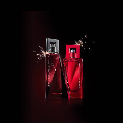 Frasco vermelho-escuro de Attraction Desire Para Ele Deo Colônia e frasco vermelho do Attraction Desire Para Ela Deo Parfum com faiscas ao redor. Fundo preto. 