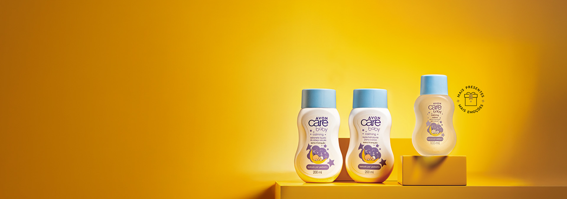 Banner com fundo amarelo e elementos incluem três produtos Avon Care Baby com embalagens brancas e tampas azuis sobre plataformas amarelas. Texto: "mimos cheios de amor e doçura para a criançada."