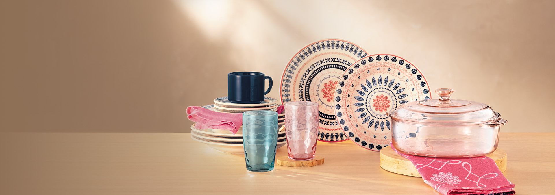 Banner em fundo bege. Em destaque, uma mesa posta com pratos decorativos, copos coloridos, um bule e toalhas. Texto: "Mesa Posta. Detalhes que encantam e transformam suas refeições em celebrações."