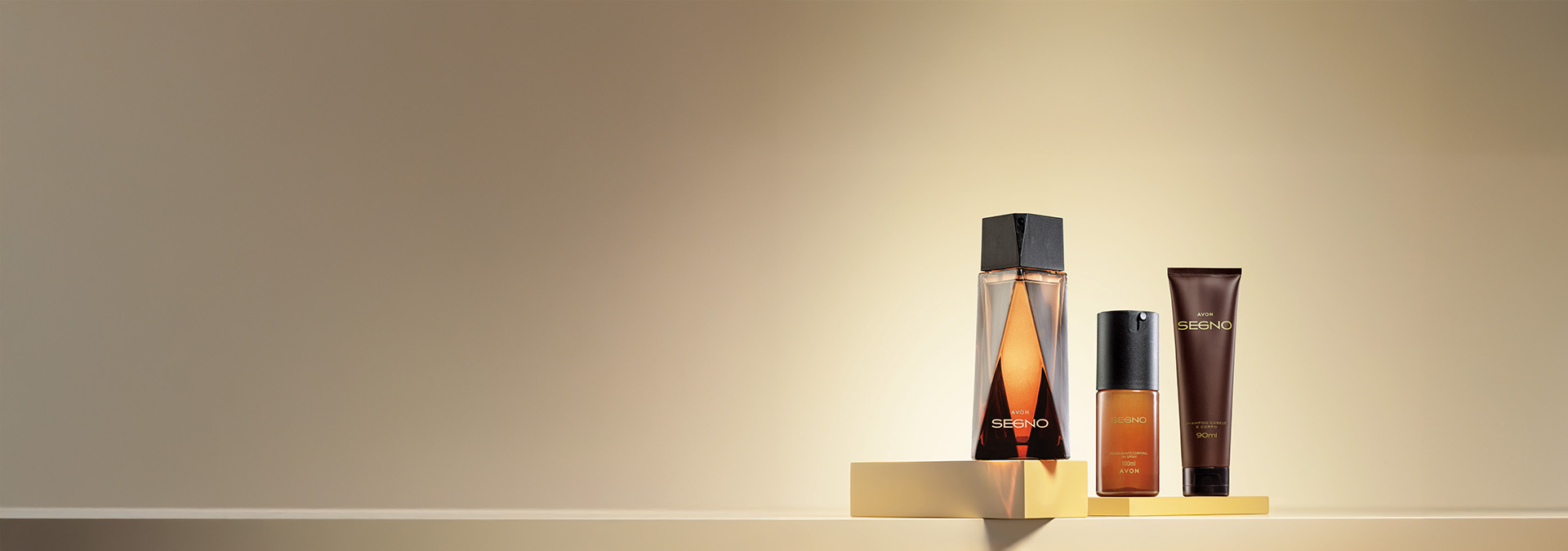Banner com fundo dourado elegante. Elementos incluem perfume, loção pós-barba e creme hidratante da linha Avon Segno sobre bases douradas. Texto: "Masculino: presentes ideais para celebrar os homens."