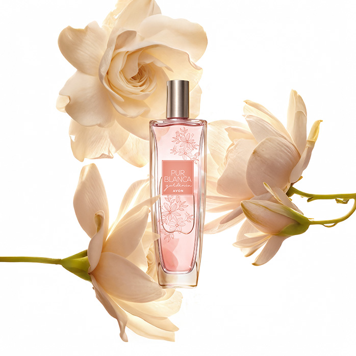 Frasco da fragrância Pur Blanca Gardênia, rodeada de flores em tom creme, em fundo branco.