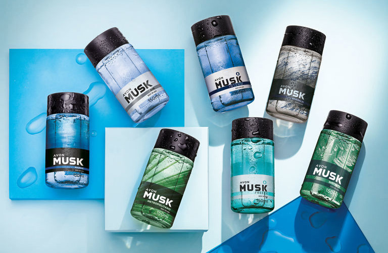 Sete frascos de body splash masculino Musk em tons de azul e verde sobre blocos geométricos coloridos.