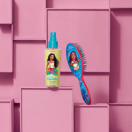 Frasco amarelo com spray azul da Colônia Moana com escova para cabelos azul com estampa Moana, sobre caixas rosas, que compõem o fundo.