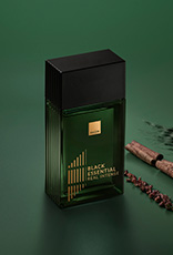 Fragrância Black Essential Real com ingredientes como pimentas e plantas, em fundo verde.