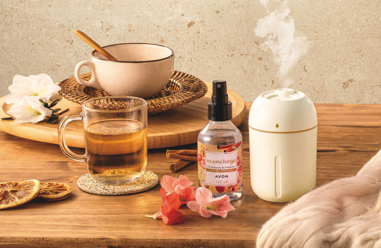 Momento de aromaterapia com difusor de vapor, spray e chá sobre mesa de madeira, transmitindo paz e relaxamento.