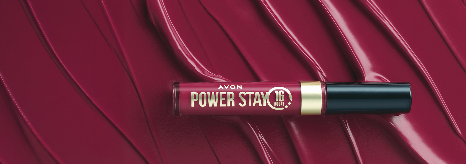 Banner com fundo em tom de vinho, apresentando o batom líquido Avon Power Stay. O produto tem embalagem elegante e destaca a cor vibrante. O texto sugere longa duração e lábios deslumbrantes.