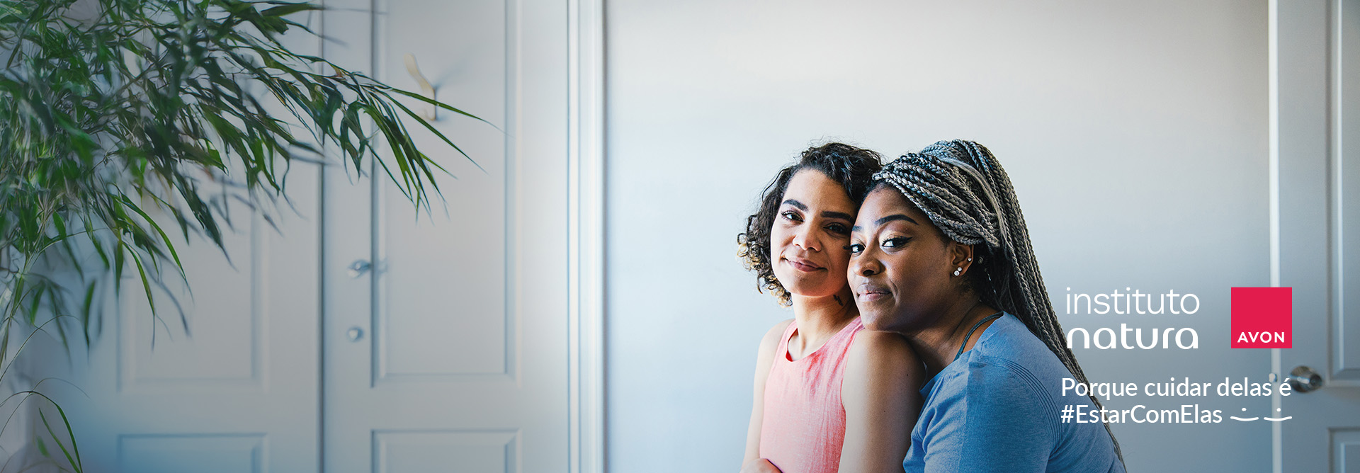 Imagem mostra mulher morena de cabelos curtos e cacheados e mulher negra de cabelos trançados e longos. Ao lado, a frase "Porque cuidar delas é #EstarComElas". Logos do Instituto Natura e da Avon.