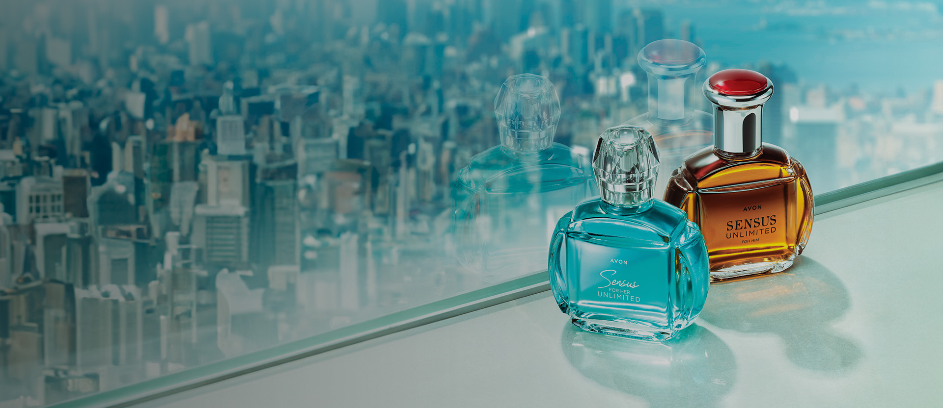 Banner con fondo difuminado de ciudad. Se presentan dos frascos de perfume: uno azul y otro ámbar. Texto: "¡Las mejores fragancias! Descubre nuestros deliciosos y frescos aromas".