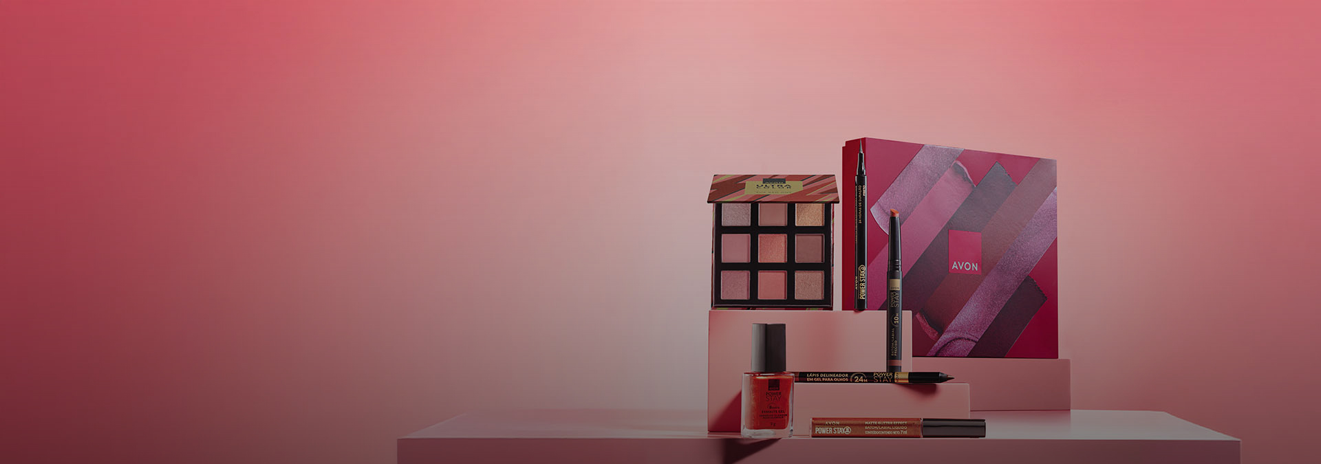 Banner com fundo rosa degradê. Elementos em plataformas geométricas destacam paleta de sombras, batom líquido, lápis delineador e esmalte. 