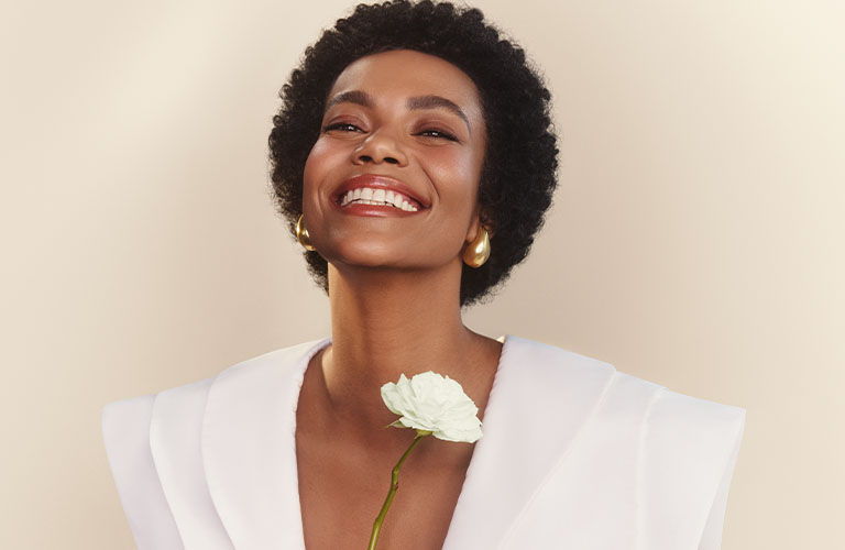 Close up mujer con afro sosteniendo una flor.