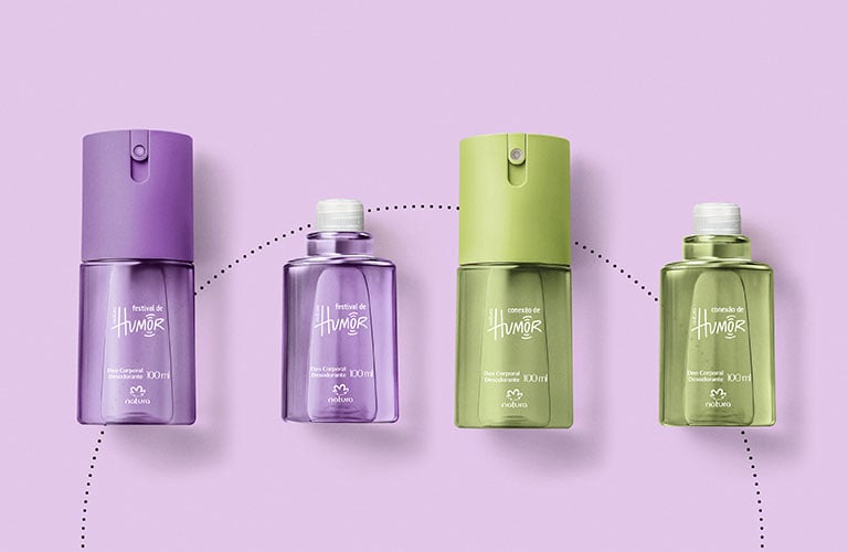 Cuatro desodorantes corporales Natura (Humor, Luna, SRN) en colores morado, verde, dorado y gris, junto a sus respectivos envases de recarga, dispuestos en un patrón circular sobre un fondo lila.