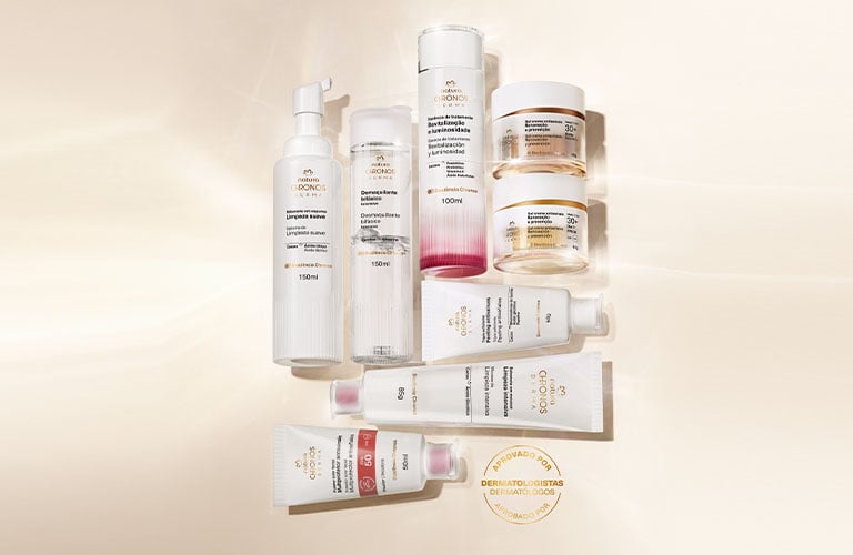 Foto de un conjunto de productos de la línea Chronos organizados sobre una superficie beige. Los envases incluyen frascos, tubos y tarros, todos con diseño limpio y etiquetas visibles.