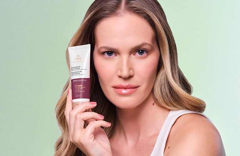 Modelo con el cabello corto y con ondas, sosteniendo un producto de la línea reconstrucción de Lumina.