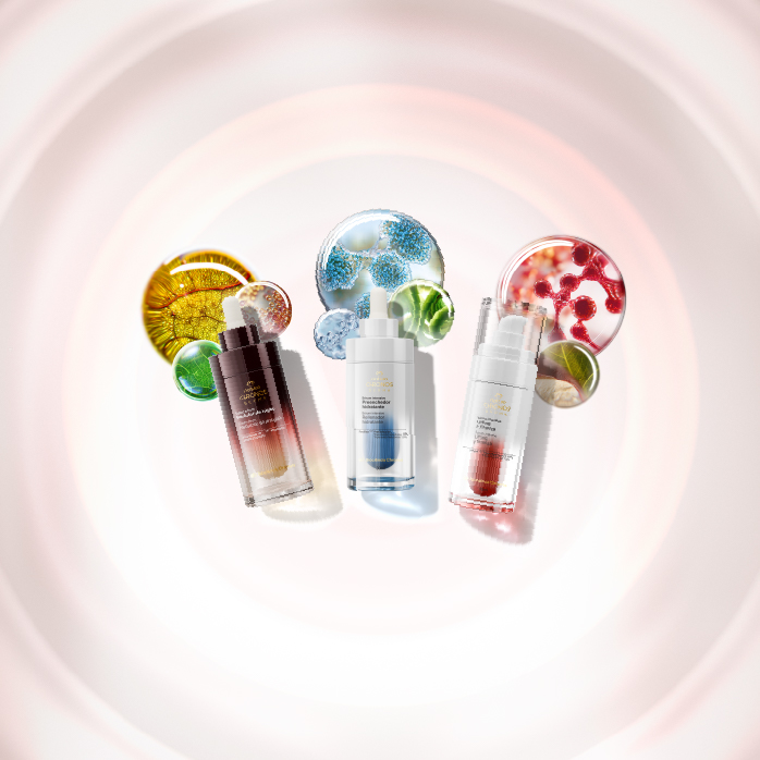 Imagen con fondo claro que muestra tres sérums de la línea Natura Chronos sobre una superficie a la derecha, iluminados por un rayo de luz.