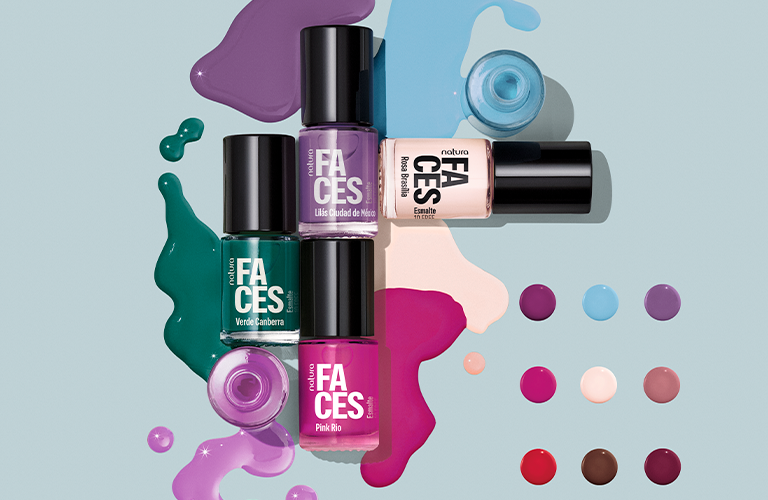 Foto de esmaltes Natura Faces sobre fondo celeste. Cuatro frascos en colores verde, púrpura, rosa y nude con manchas de esmalte derramado. A la derecha, una paleta de doce puntos de colores muestra la variedad de tonos disponibles.