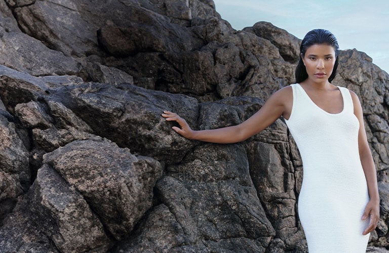 Close up de modelo de vestido blanco en la playa