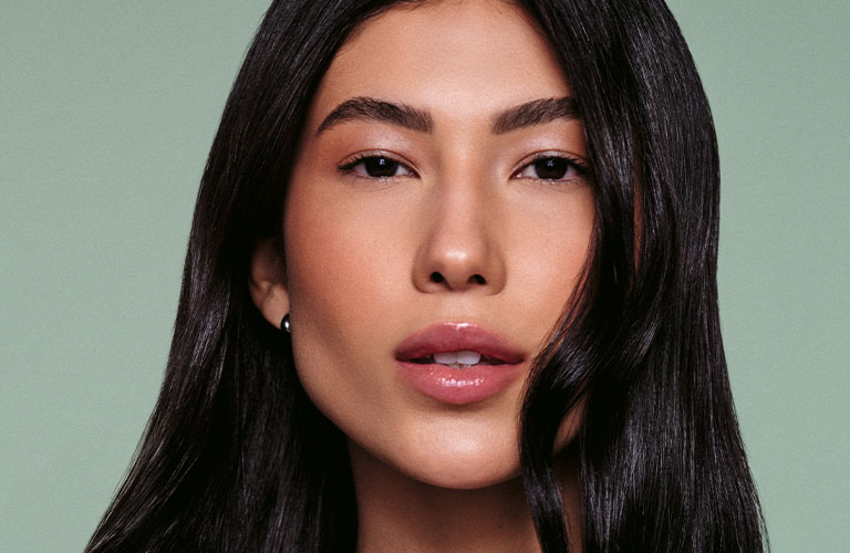 Mujer de cabello ondulado utilizando una blusa blanca.