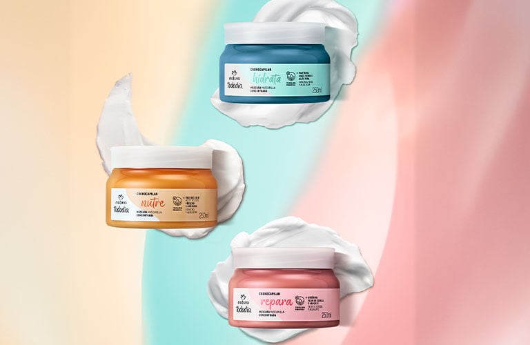 Foto de los tres potes de máscara capilar Tododia Cronocapilar, con fondo en tonos pastel. Los envases en azul, naranja y rosa aparecen sobre trazos de textura cremosa.